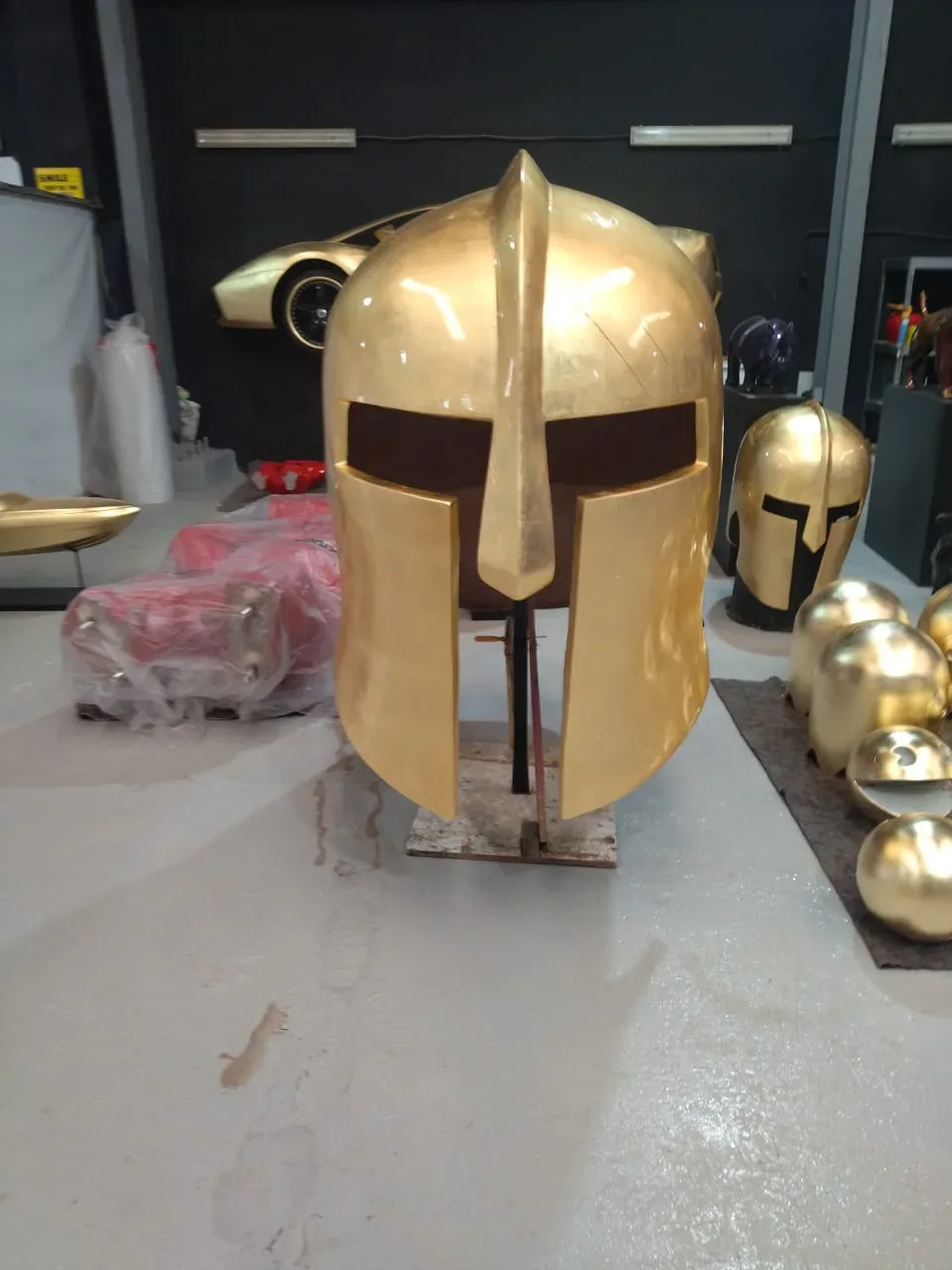 Casque spartiate doré présenté dans l’atelier.