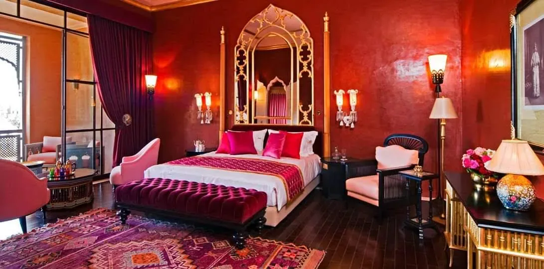 Chambre rouge décorée de mobilier, miroirs et détails dorés.
