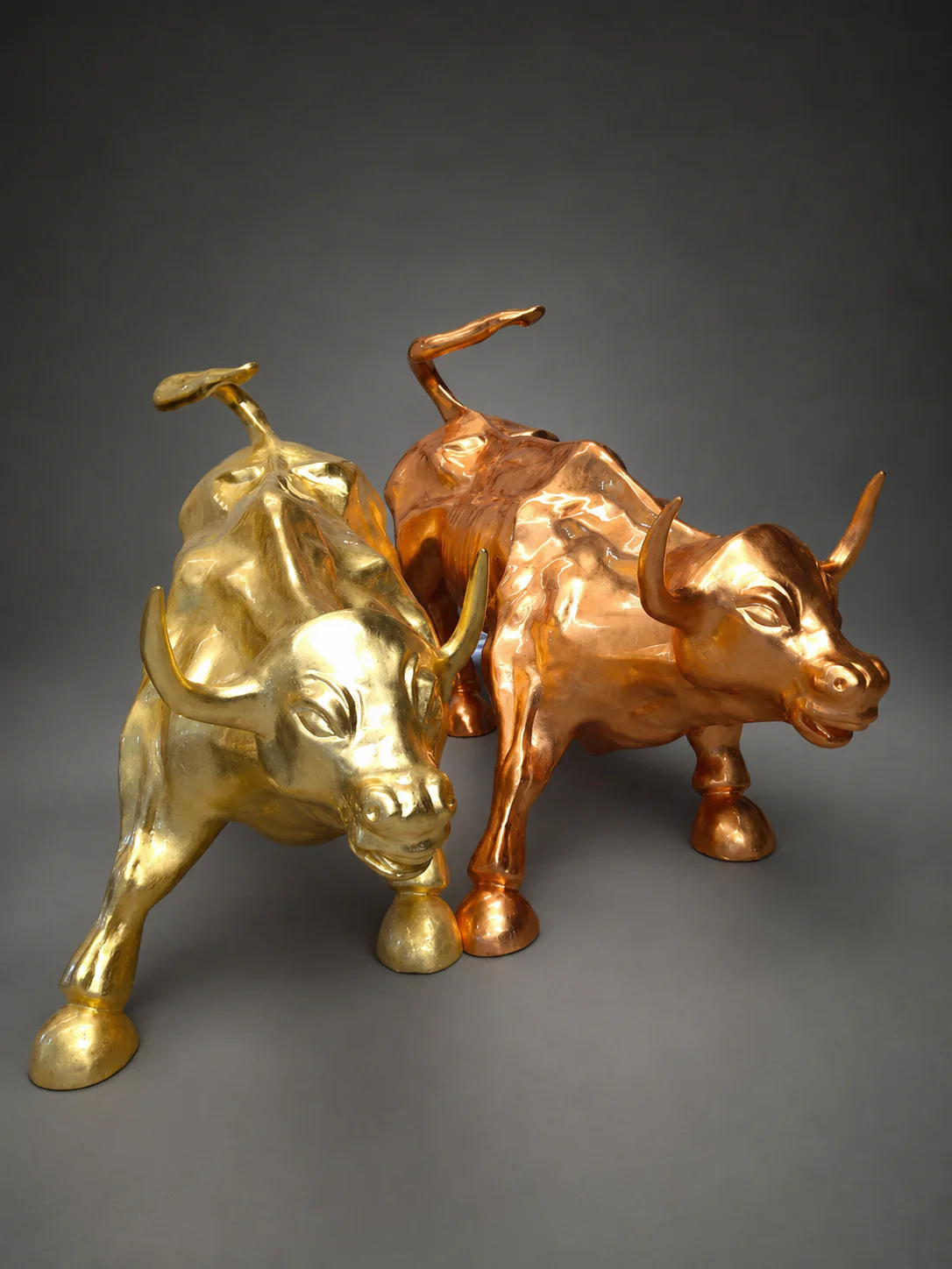 Deux sculptures de taureaux dorés côte à côte.