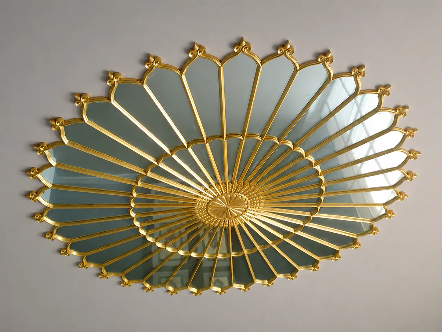 Miroir soleil décoratif aux rayons dorés.